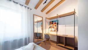 Camera d'albergo moderna con un letto, una scrivania, una sedia e un'ampia finestra con tende.