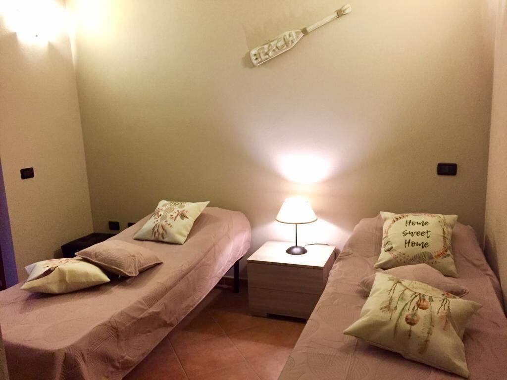Un dormitorio con dos camas individuales, una mesita de noche con lámpara y almohadones decorativos.