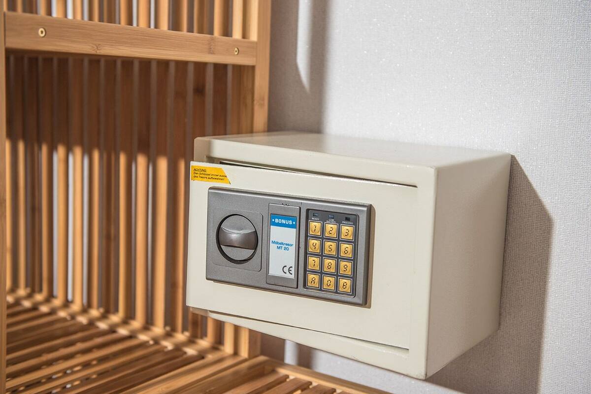 Un coffre-fort doté d’un clavier et d’un emplacement supplémentaire pour carte, fixé au mur et agrémenté d’un motif en lambris de bois.