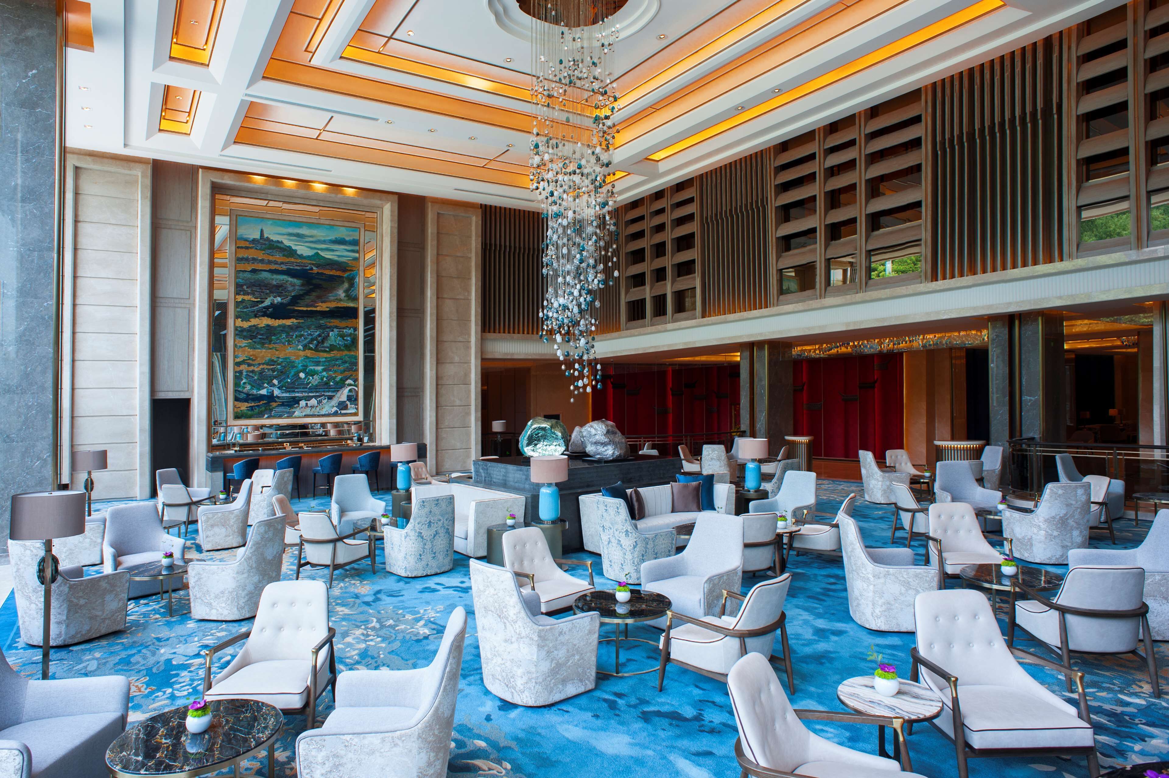 A spacious lobby with modern seating, a large chandelier, and a prominent painting on the wall.