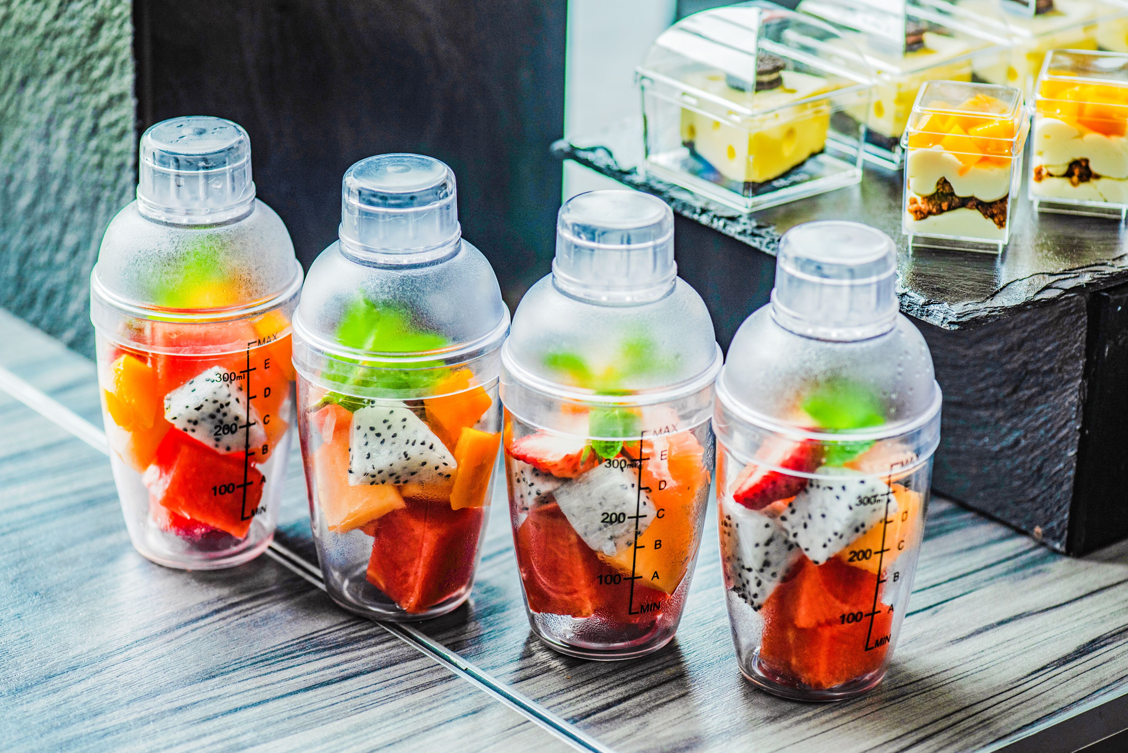 Four clear plastic bottles filled with fruit and a measuring scale.