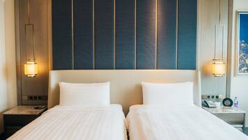 Ein Hotelzimmer mit zwei Betten, einem Holz-Kopfteil, Nachttischlampen, einem Nachttisch mit Telefon und einem gerahmten Bild an der Wand.
