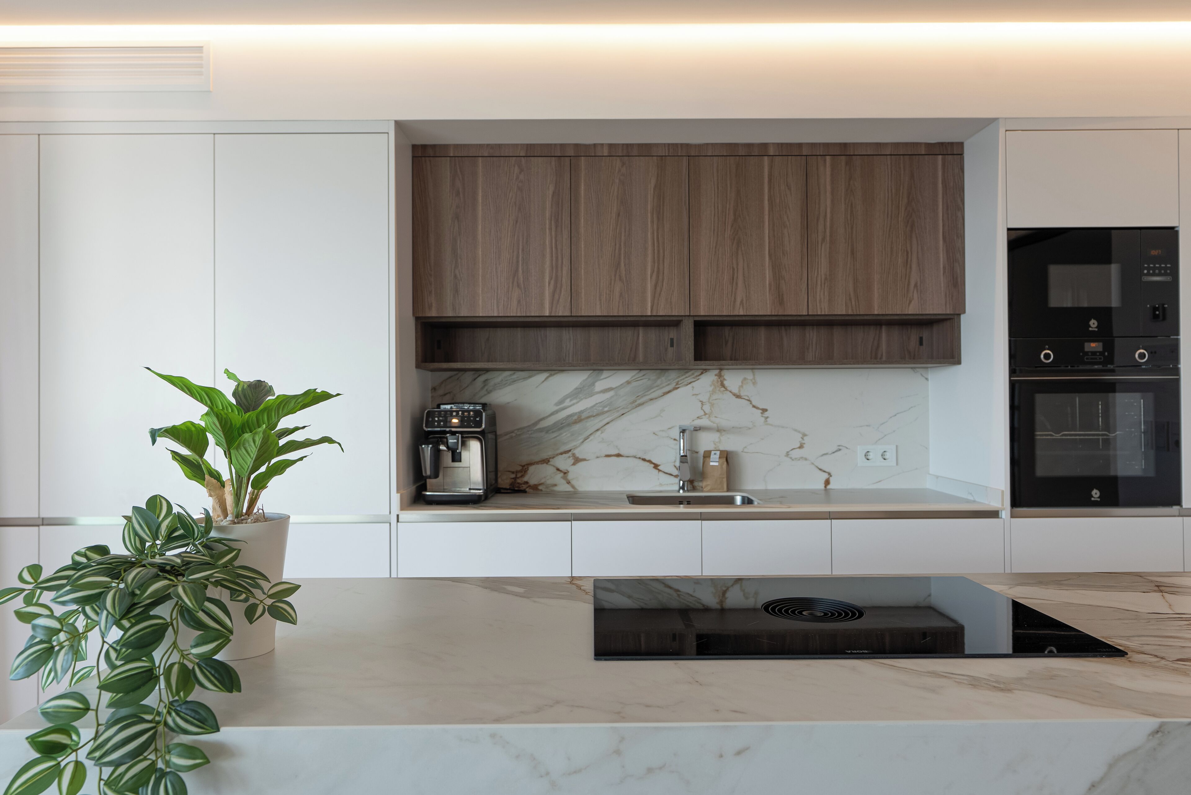 Una cocina moderna con estufa integrada, cafetera y salpicadero de mármol.