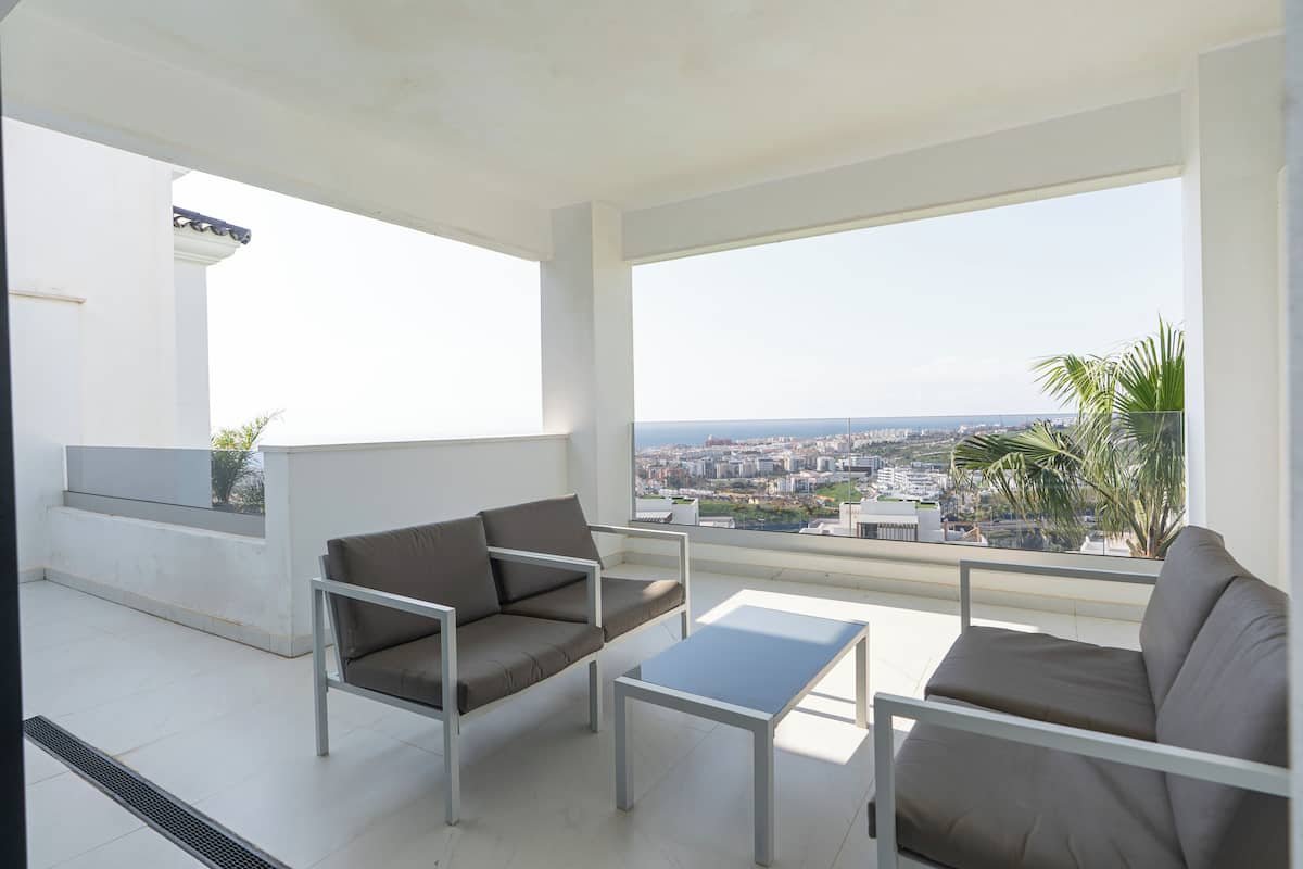 Un balcon avec un canapé, une petite table et une vue sur le paysage urbain.