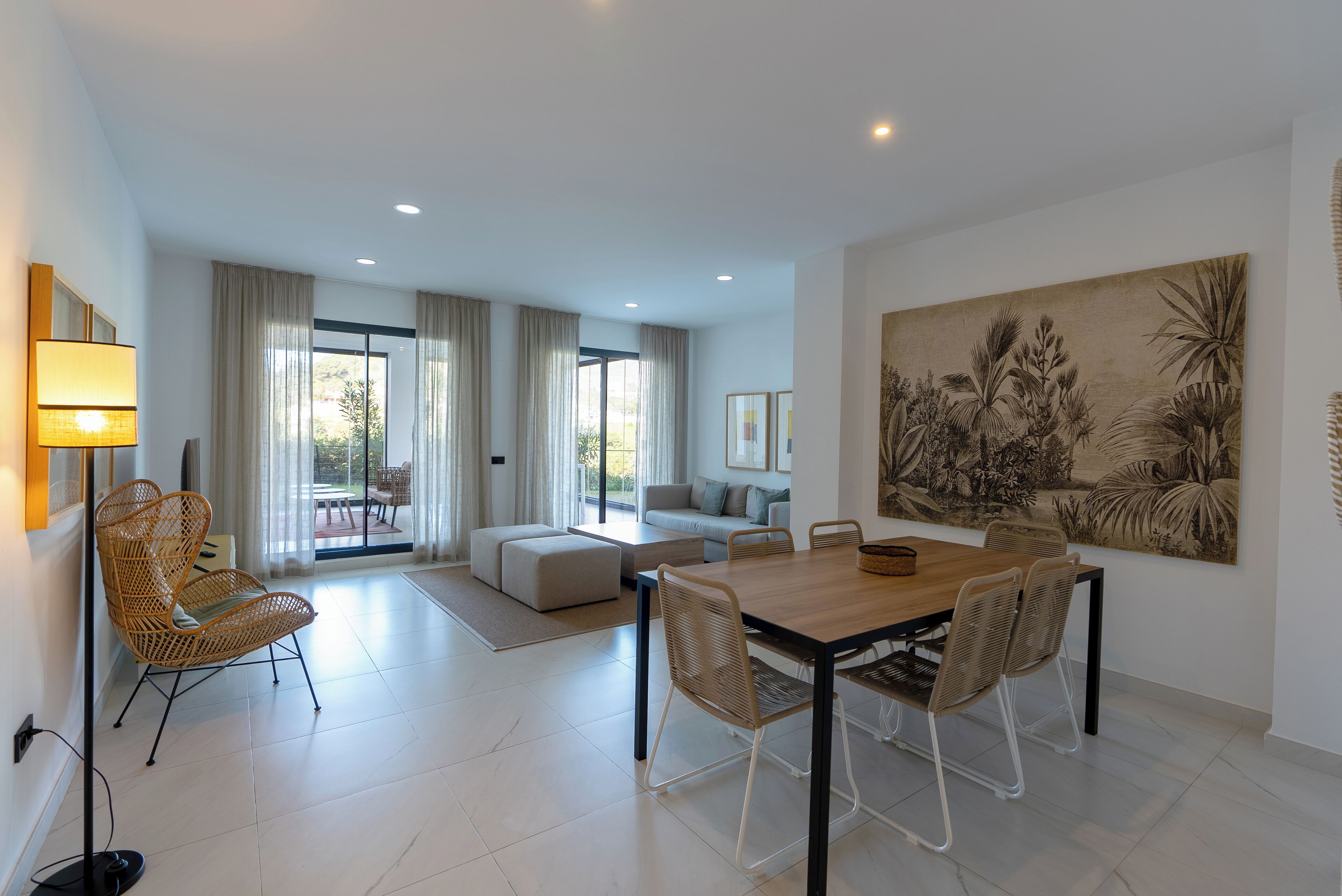 A spacious living area with a dining table, chairs, a sofa, and a large painting on the wall.