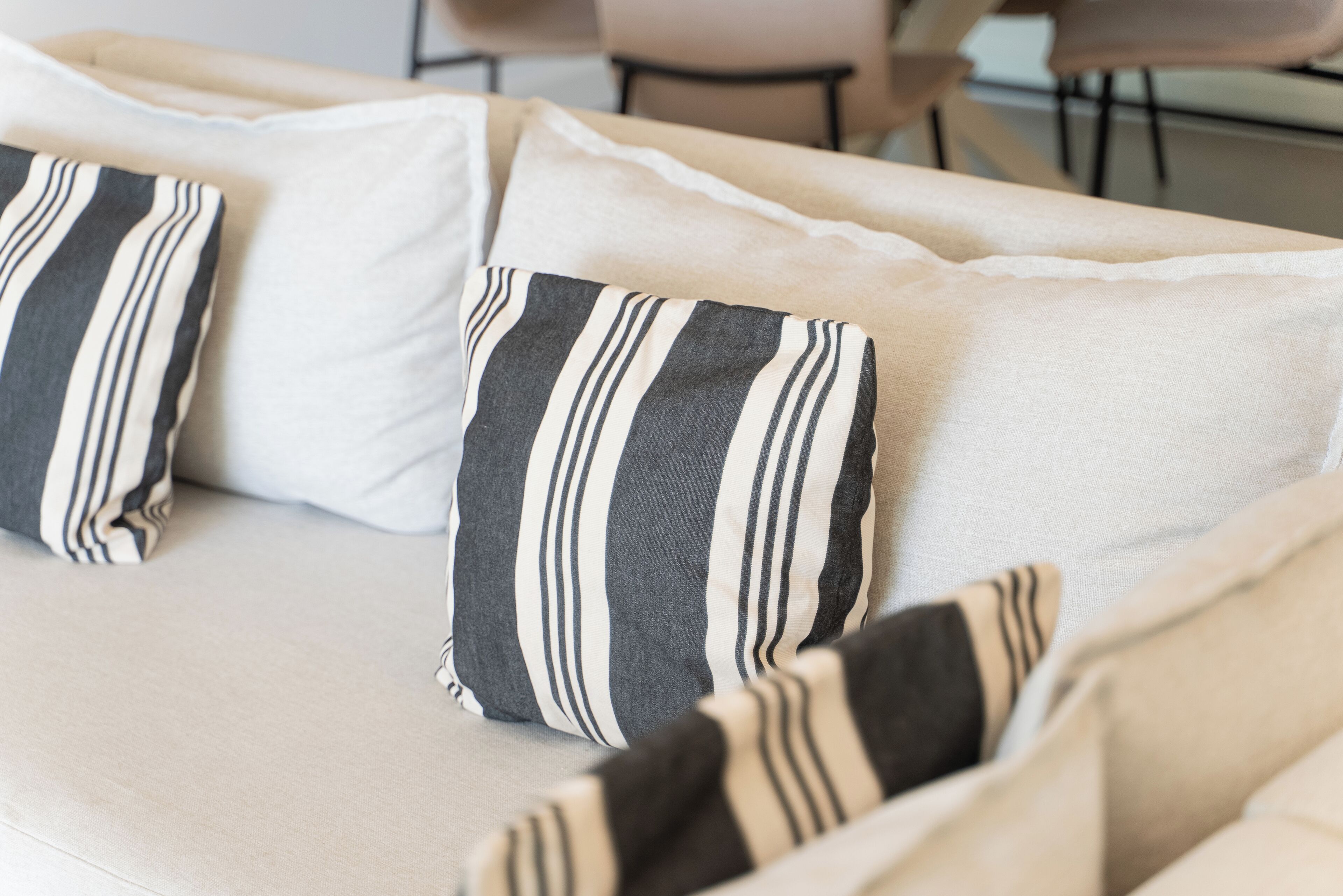 A sofa with striped pillows and a light-colored cushion.