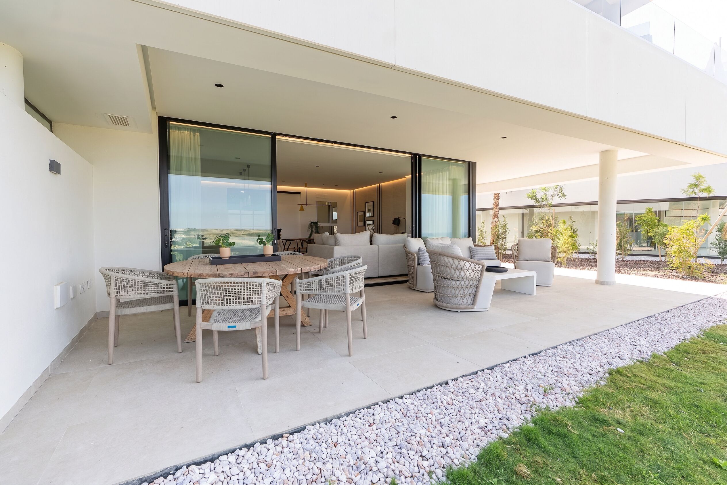 A modern outdoor patio with a dining table and chairs, a sofa, and a lounge chair.
