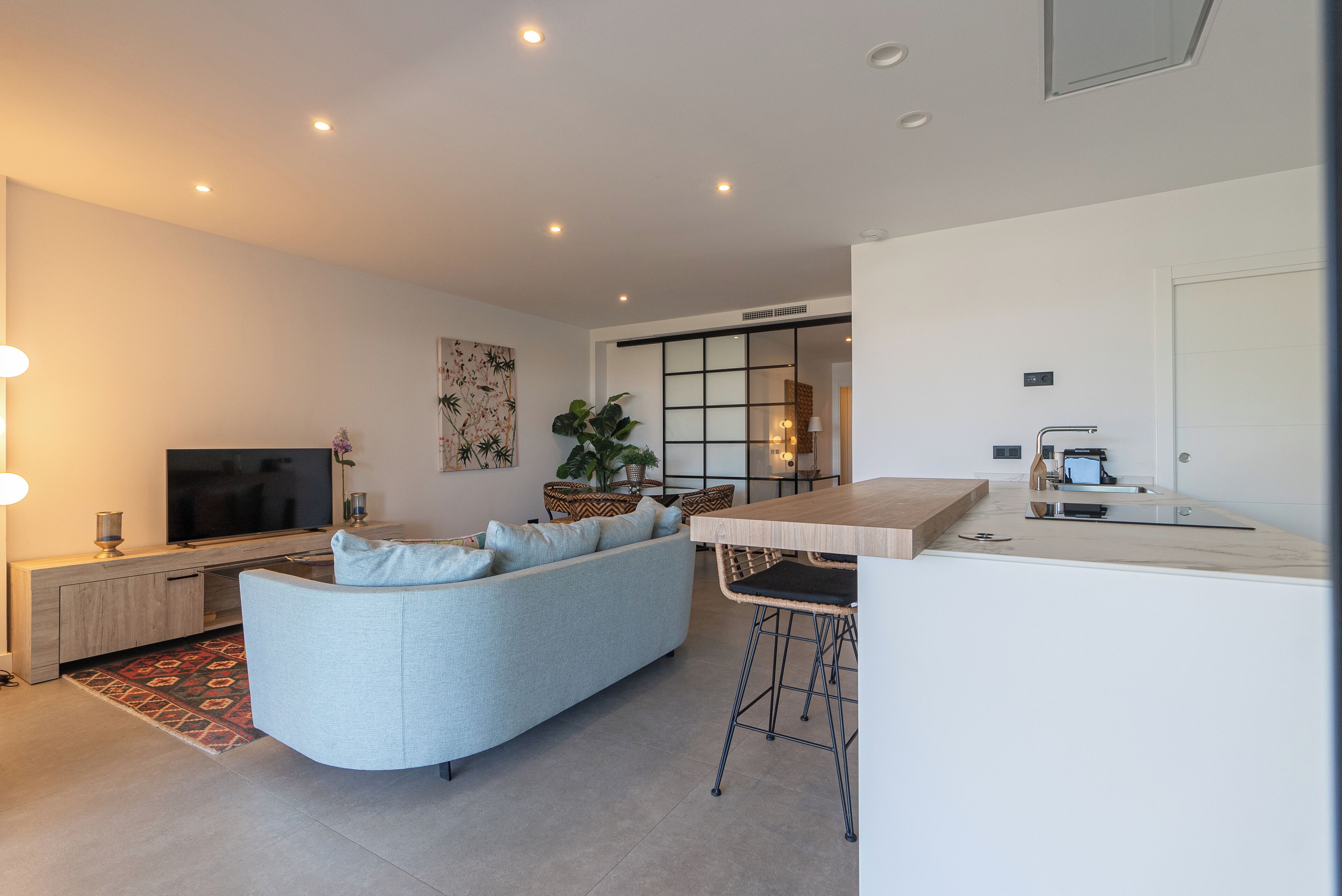 Una sala de estar moderna con un sofá, un televisor y una cocina con barra.