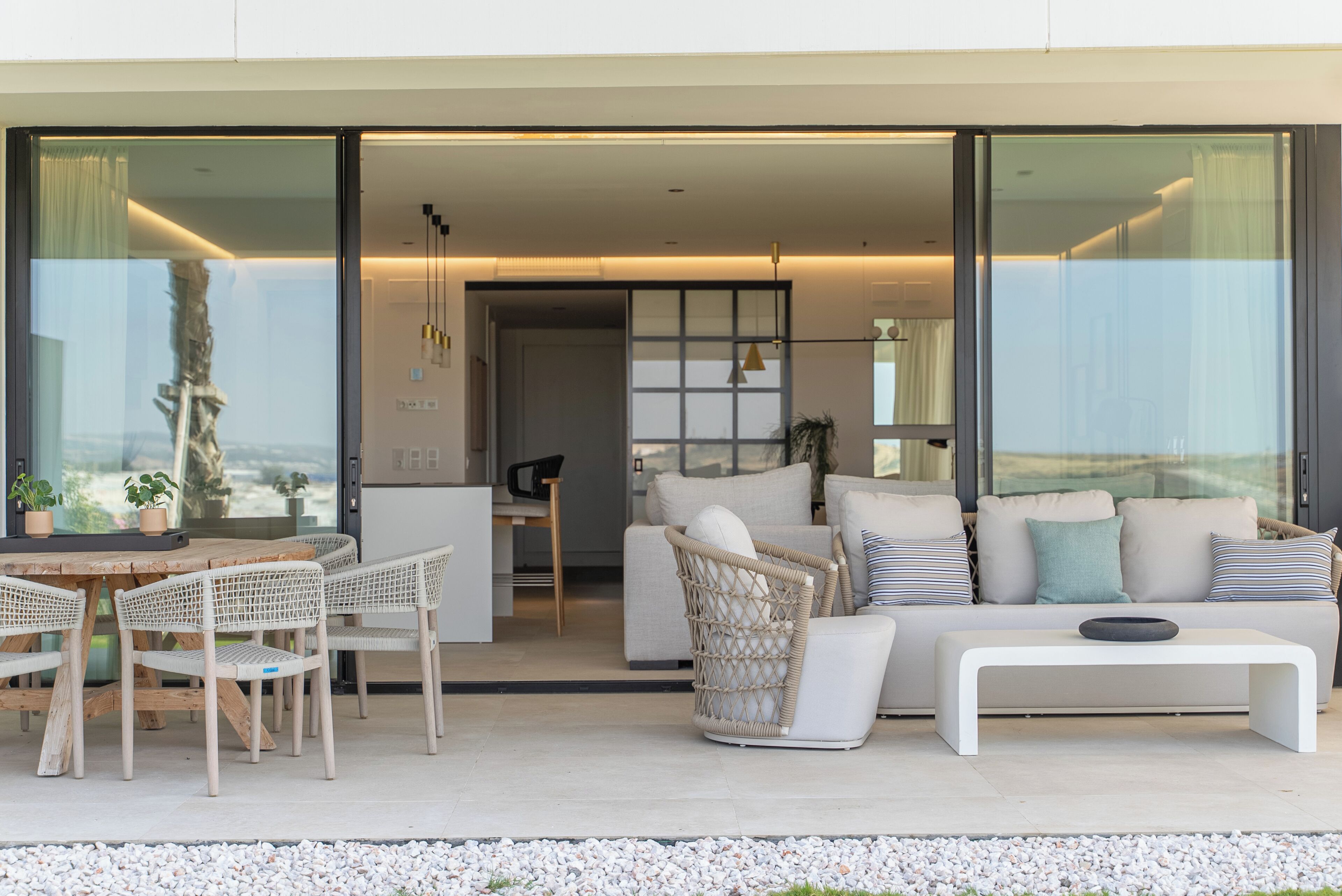 Ein modernes Interieur mit einer Sitzecke, einem Esstisch und Blick durch große Glasüren.