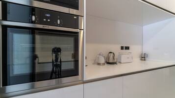 Una cocina moderna con horno empotrado y microondas, además de cafetera y tostadora sobre la encimera.