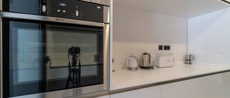 A modern kitchen with a built-in oven and microwave, a coffee maker, and a toaster on the countertop.