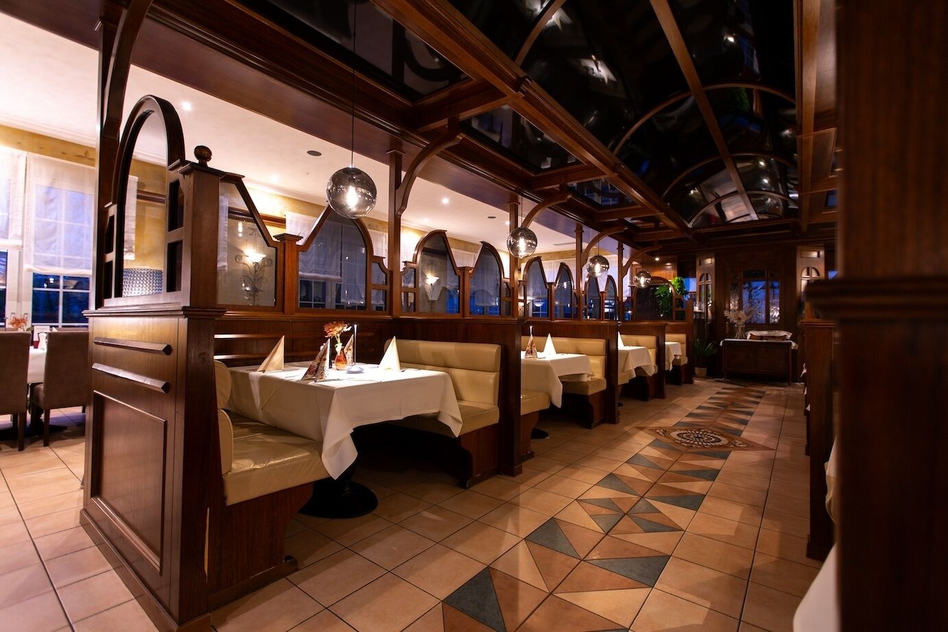 A restaurant with booths, tables, and a patterned floor.
