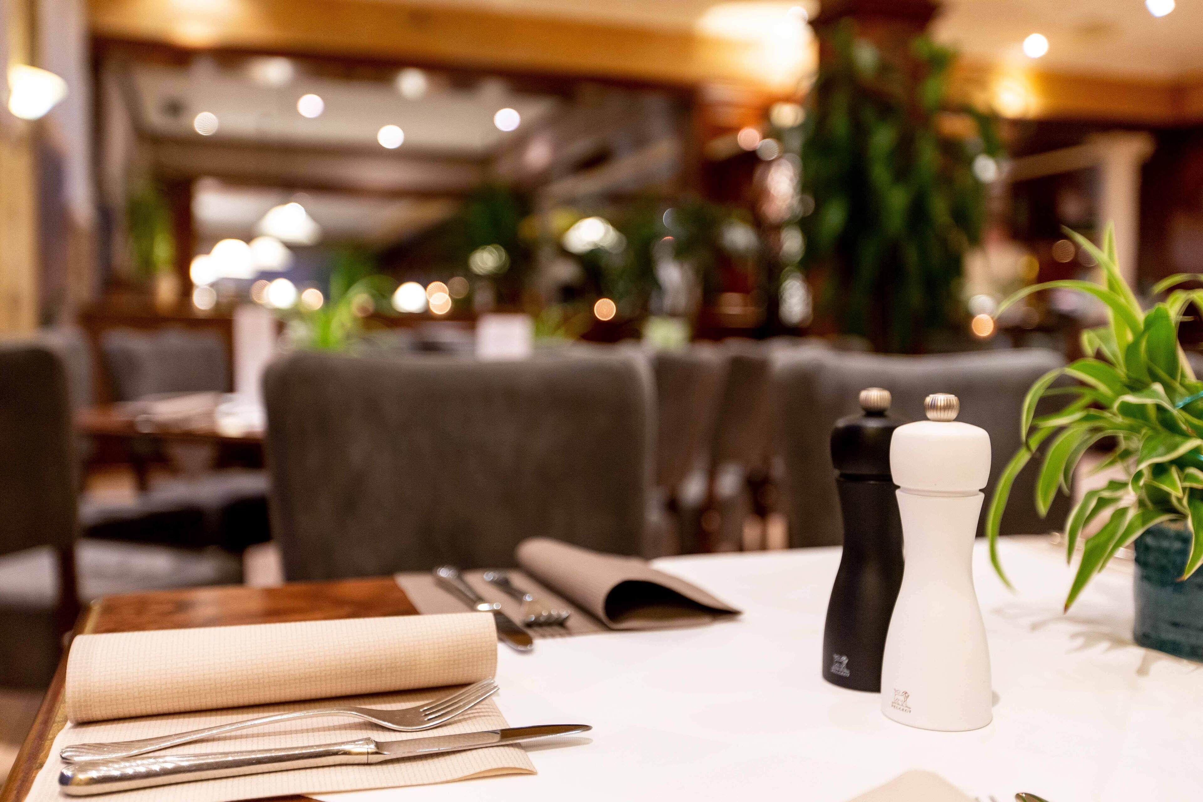 A restaurant table set with a napkin, cutlery, and a salt and pepper shaker.
