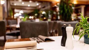 Una mesa de restaurante dispuesta con servilleta, cubiertos y salero y pimentero.