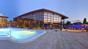 A modern hotel with a large outdoor pool, lounge areas, and a well-lit facade. - Korbstadthotel Krone (Lichtenfels)
