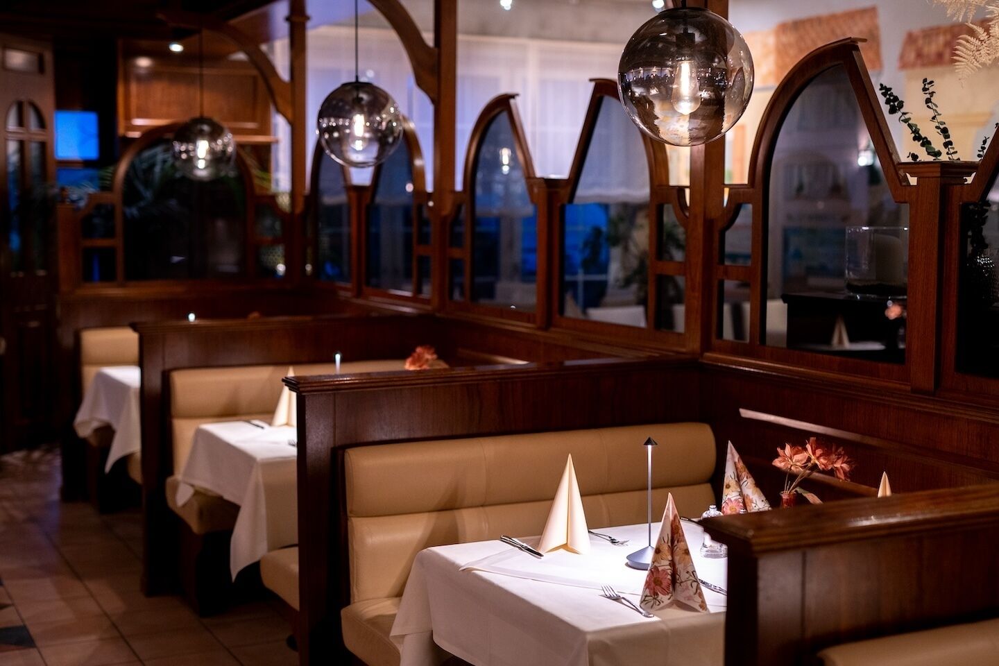 A restaurant with wooden booths, white tablecloths, and decorative conical centerpieces.