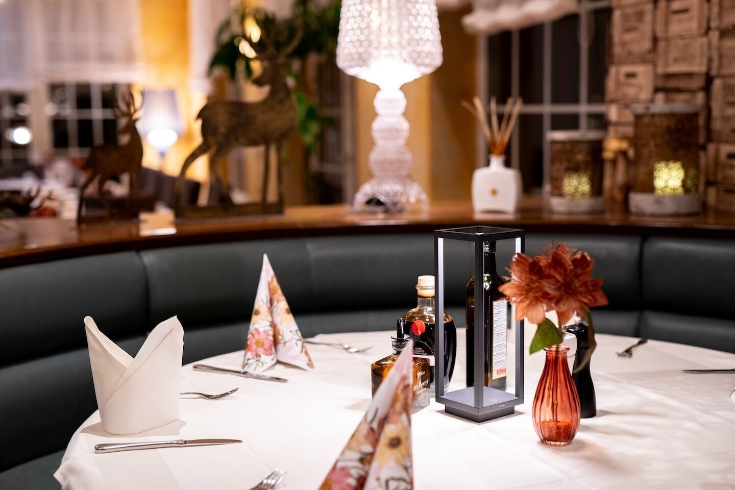 A dining table set with a white tablecloth, silverware, folded napkins, and a floral centerpiece.