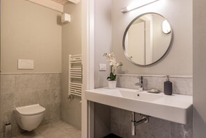 Un baño moderno con inodoro, lavabo con espejo y un perchero para toallas.