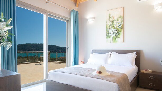 Ein Schlafzimmer mit einem großen Bett, einem Nachttisch, einer Kommode und Meerblick vom Balkon.