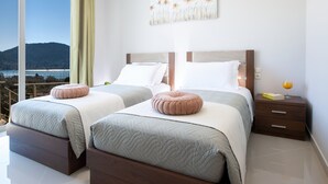 Ein modernes Schlafzimmer mit zwei Betten, Meerblick und einem Gemälde an der Wand.