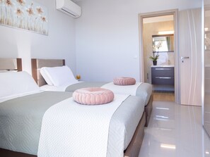 Een hotelkamer met twee bedden, een badkamer en een deur naar een andere kamer.