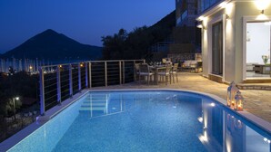 Ein Swimmingpool mit Bergblick, ein Essbereich mit Außenbestuhlung und ein Gebäude mit einem Balkon mit Blick auf den Pool.