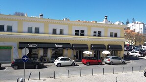 A building with multiple storefronts, including a cafe and a charcuterie. - Experience relaxing holidays (Estoril)
