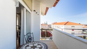 A balcony with a tiled table and chairs, a view of neighboring buildings, and a clear sky. - Experience relaxing holidays (Estoril)