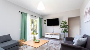 Una sala de estar moderna con un sofá, una mesa de centro, un televisor y una planta.
