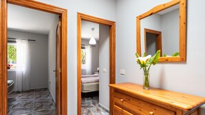 Una habitación de hotel con un aparador de madera, un espejo y un florero con flores.