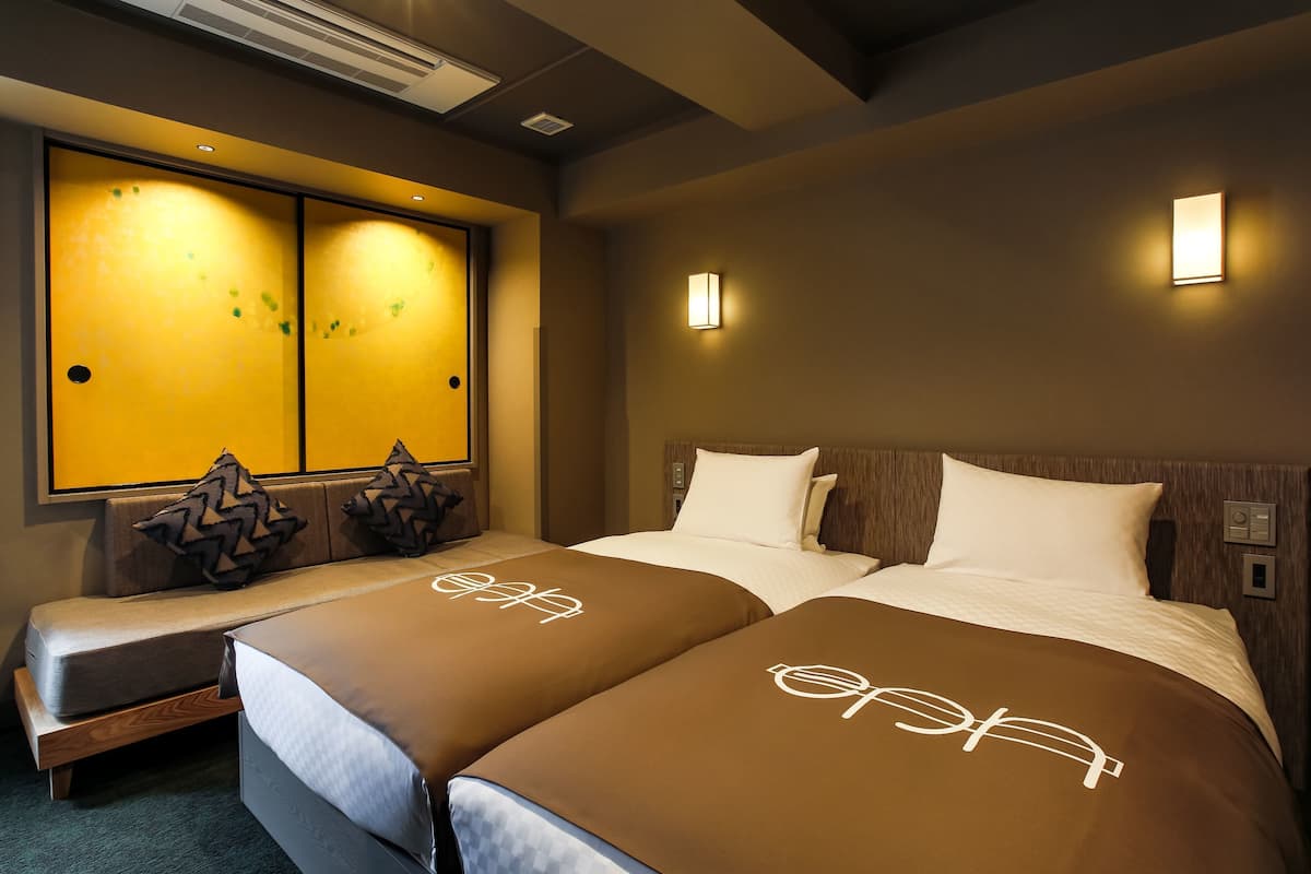A hotel room with two beds, a sofa, and a large window with a view.