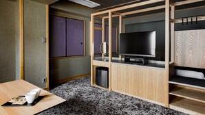 A compact hotel room with a wooden TV stand, a small seating area with a table, and a compact wardrobe. - eph TAKAYAMA (Takayama)