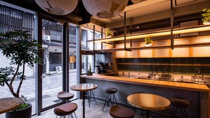 A modern bar area with stools, a bar counter, and a large potted plant. - eph TAKAYAMA (Takayama)