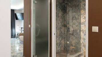 A modern bathroom with a glass-enclosed shower, marble flooring, and a brown accent wall.