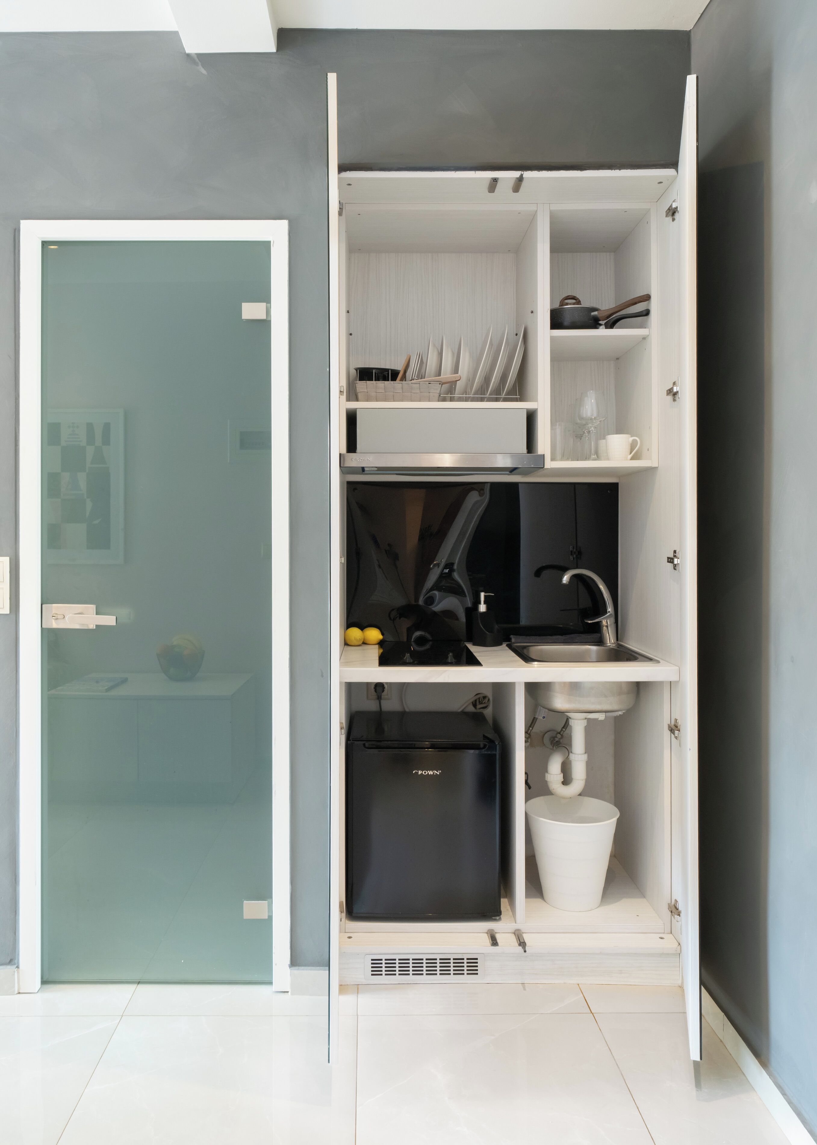 A compact kitchen with a built-in dishwasher, a sink, and a small refrigerator.