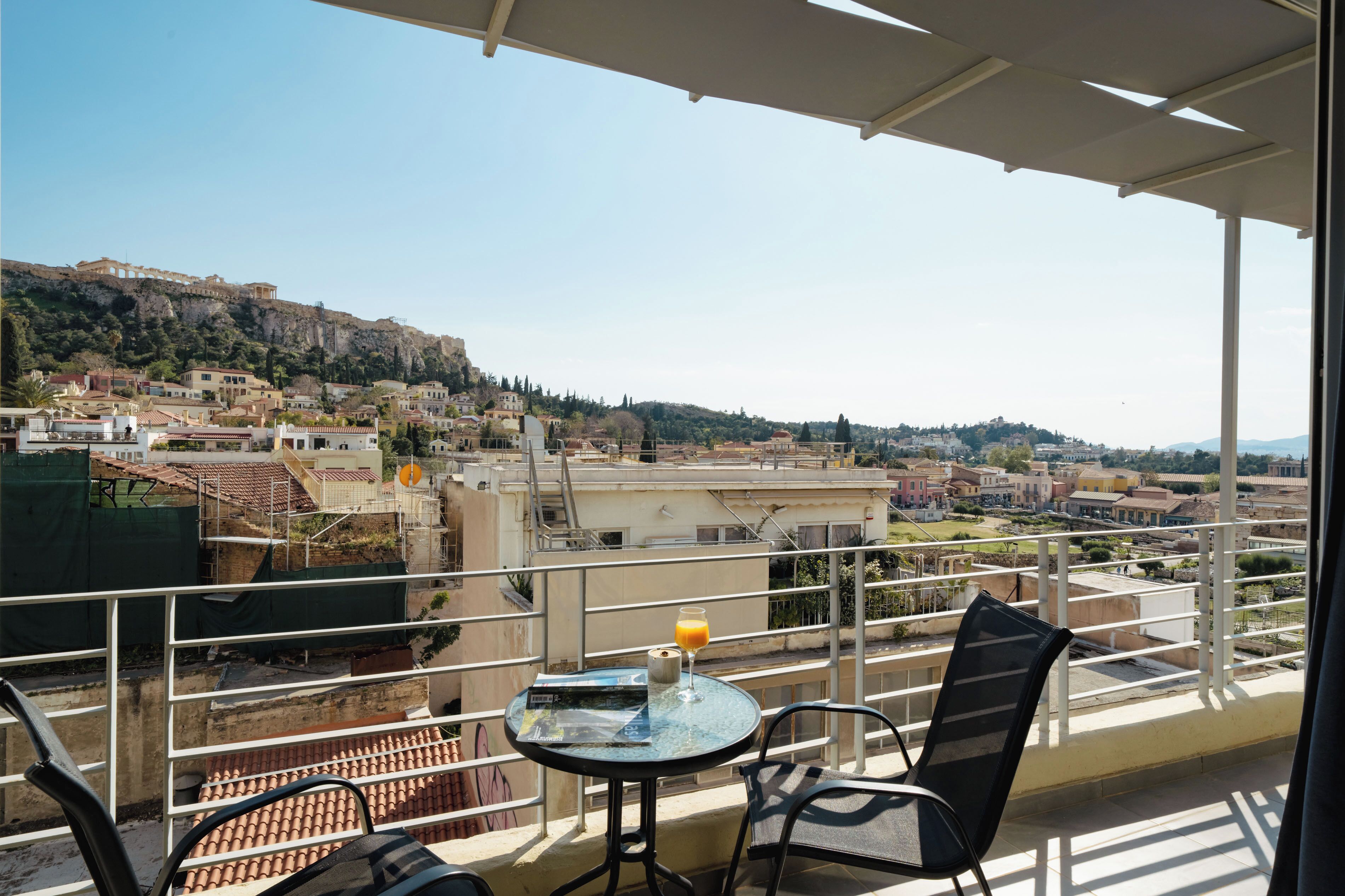 A balcony with a table, chairs, and a glass of orange juice.