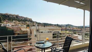 A balcony with a table, chairs, and a glass of orange juice.