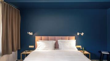 Una habitación de hotel con una cama grande, dos mesitas de noche, una lámpara y una ventana con cortinas.