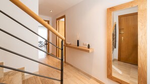 A modern interior with a wooden staircase, a floating shelf with decorative items, and a large mirror. - Duplex Ègara by Petit Luxe (Terrassa)