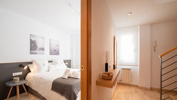 A modern bedroom with a bed, bedside table, and artwork on the wall. - Duplex Ègara by Petit Luxe (Terrassa)