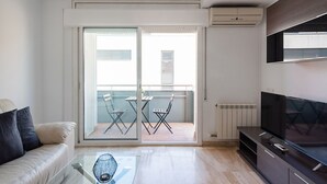 A modern living room with a glass door leading to a balcony, a flat-screen TV, and a glass coffee table. - Duplex Ègara by Petit Luxe (Terrassa)