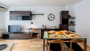 A modern kitchen with a dining table set for breakfast, a clock on the wall, and a TV in the corner. - Duplex Ègara by Petit Luxe (Terrassa)