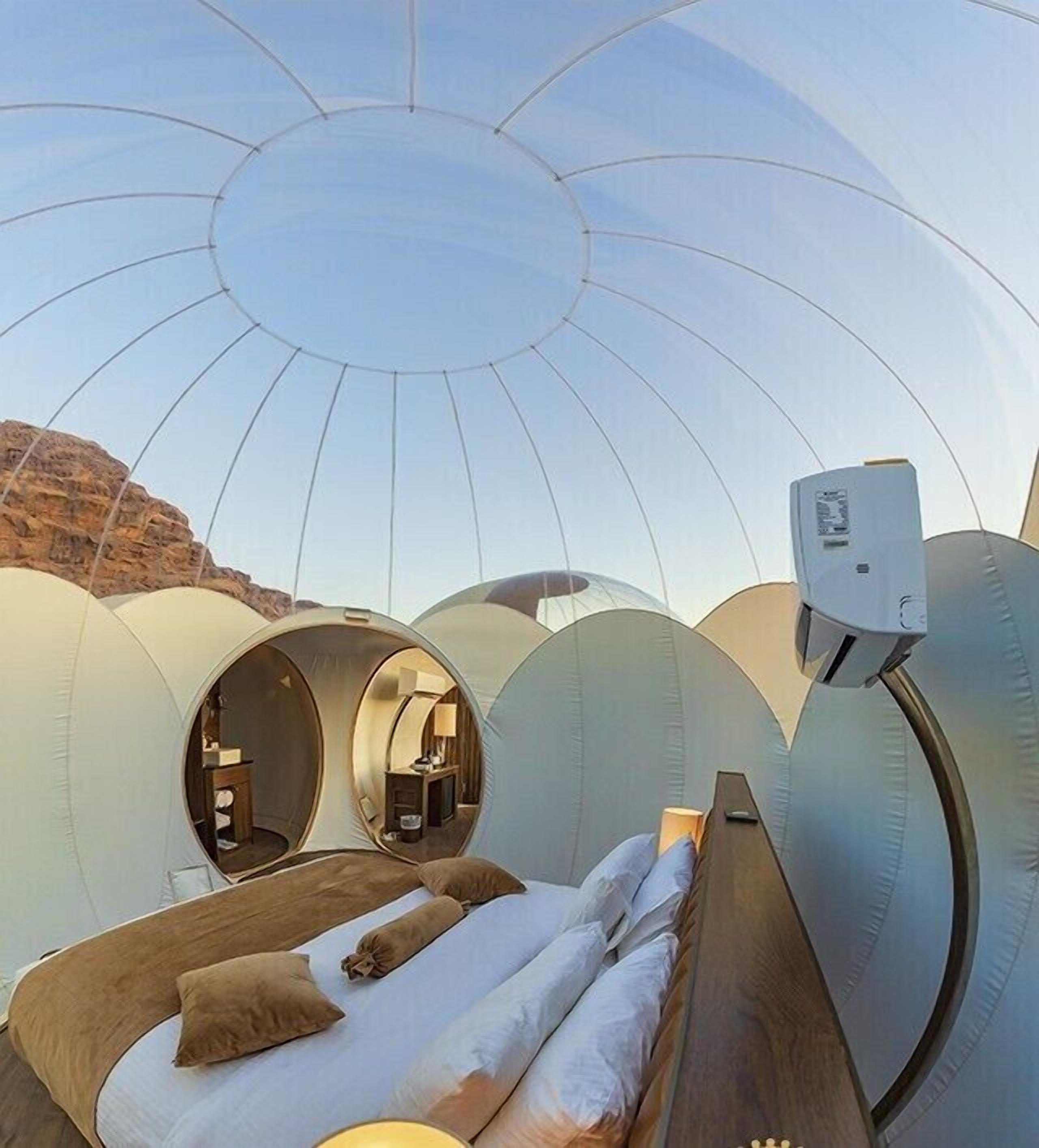 Una habitación abovedada con una cama, una mesita y un dispositivo en la pared.