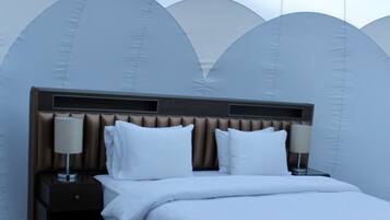 Una habitación de hotel moderna con una cama grande, dos mesitas de noche con lámparas y un diseño de techo original.