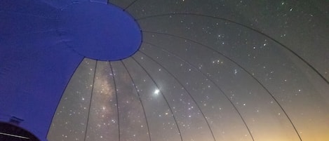 A dome-shaped observatory with a clear view of the night sky. Inside, there are two chairs and a small table.