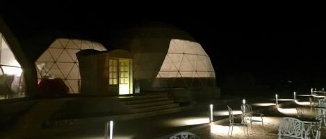 A series of dome-shaped tents with a central entrance, outdoor seating, and steps leading up to the entrance.