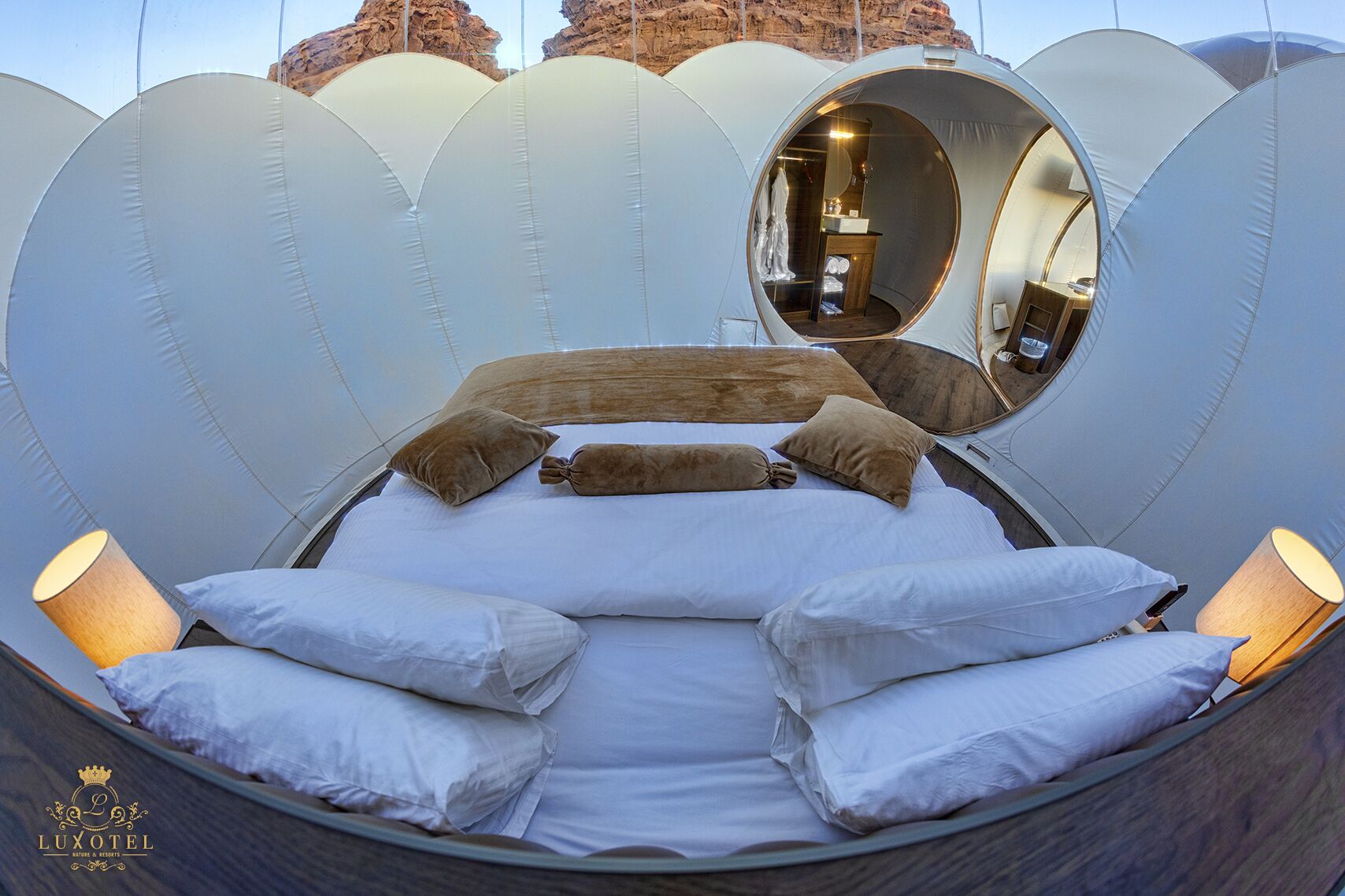 A circular, tent-like room with a bed, pillows, and a mirror.