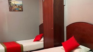 A hotel room with two beds, each with red and white bedding and a red headboard. There is a wooden wardrobe and a painting on the wall. - Stada Hotel (Kota Bharu)