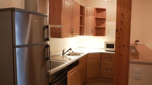 A compact kitchen with stainless steel appliances, wooden cabinets, and a microwave. - Ferienwohnung Krabbe (Kopendorf auf Fehmarn)
