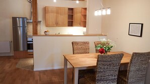A compact kitchen with wooden cabinets, a built-in oven, and a stainless steel refrigerator. - Ferienwohnung Krabbe (Kopendorf auf Fehmarn)